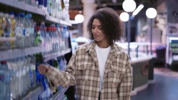 Fekete nő élelmiszer vásárlás a szupermarketben, keres vizes palackok, lassított felvétel — Stock videók