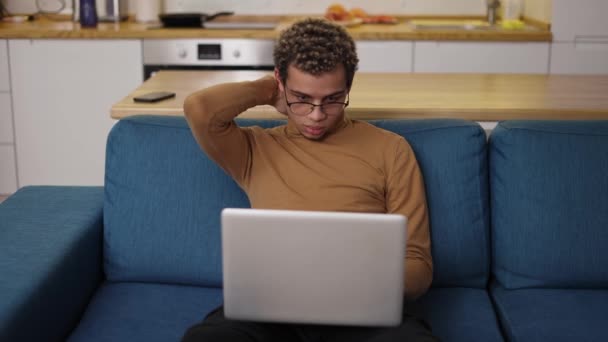 Nadopiekuńczy młodzieniec korzystający z laptopa na kanapie — Wideo stockowe