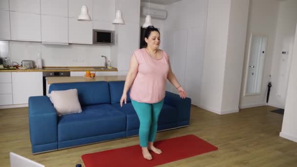 Mujer con sobrepeso realizando yoga asana en casa — Vídeos de Stock