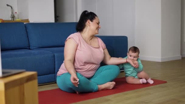 Plus size woman disturbed by her baby while sitting on the floor in meditation — Stock Video