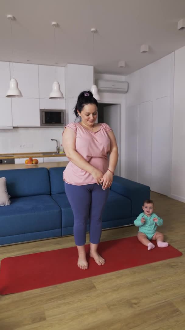 Overweighted woman doing breathe exercises while her baby playing next to her — Stock Video