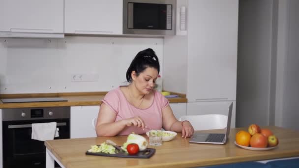 Mulher com excesso de peso comendo cereais na frente do laptop — Vídeo de Stock