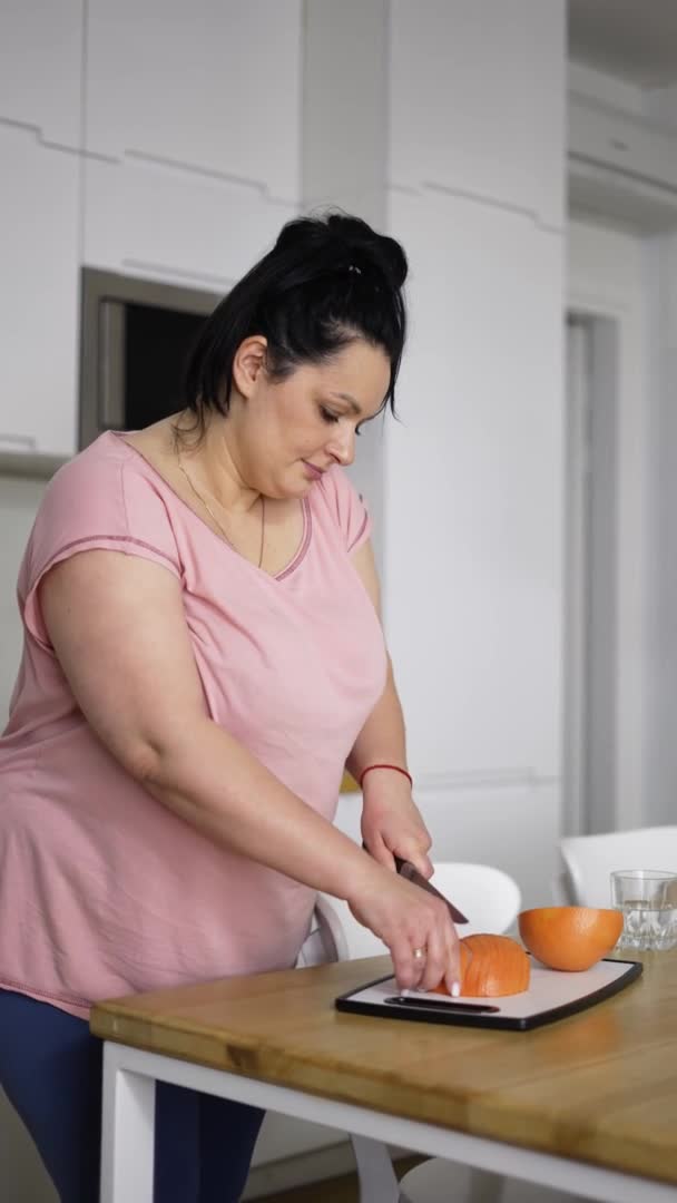 Belle femme en surpoids préparant des repas sains, coupant du pamplemousse, gros plan — Video