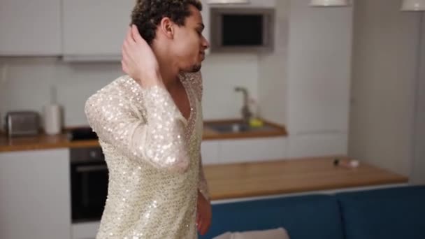 Een man in een jurk bewondert zichzelf, sensueel dansend op de keuken — Stockvideo
