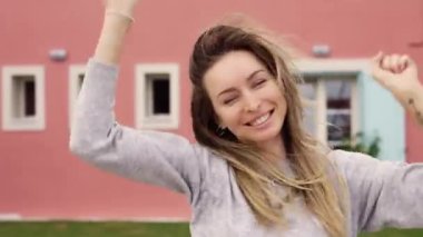 Tatmin olmuş bir bayan yeni evinin önünde elinde yeni dairenin anahtarlarıyla zıplıyor