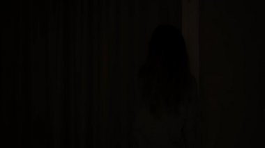Otel odasında perdeleri açan kadın balkona çıkıyor.