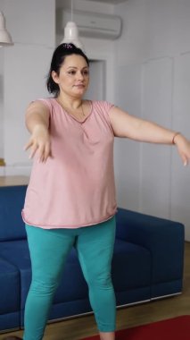 Spor giyimli esmer bir kadın. Kilo vermek için egzersiz yapıyor, evde çömelme egzersizi yapıyor.