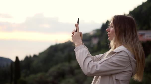 Mujer de pelo largo toma una foto con un teléfono inteligente en sus manos — Vídeos de Stock