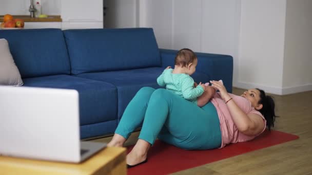 Overweighted woman doing exercises online with little baby together — Stock Video