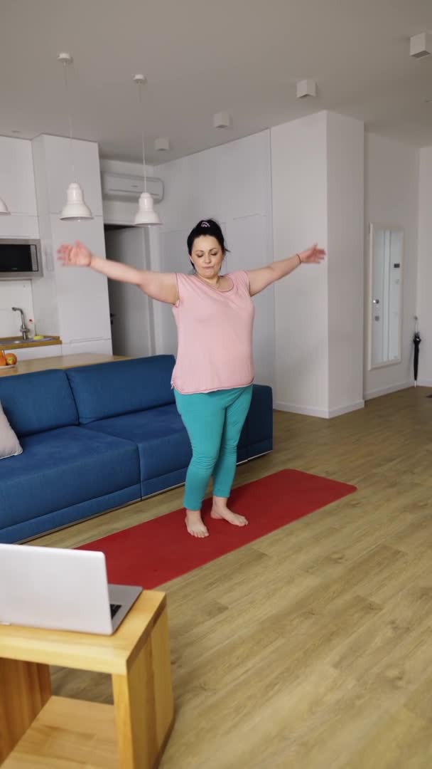 Mujer realizando yoga asana en casa con tutor en línea en laptop — Vídeos de Stock