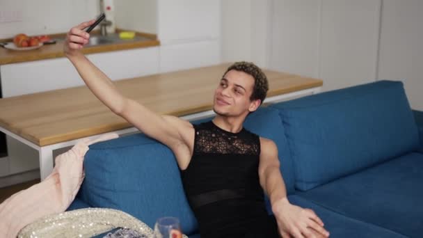 Érzéki srác ruhában szelfit csinál mobiltelefonnal a kanapén. — Stock videók