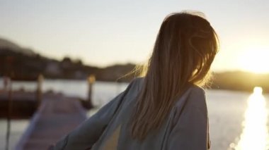 Deniz kenarındaki köprüde dönen mutlu bir kızın bulanık arkaplan görüntülerini kapatın.