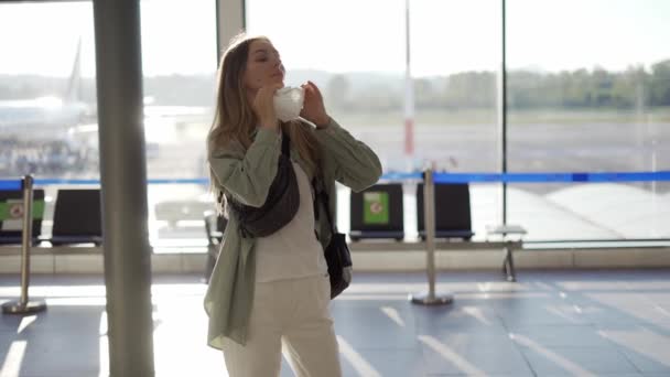 Bayan gezgin, havaalanında dikilirken koruyucu maske takıyor. — Stok video