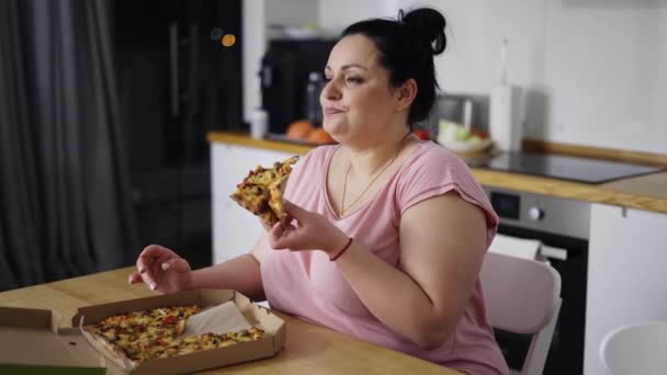 Mujer sobrecargada come con gran placer, mujer come pizza, rueda los ojos — Vídeos de Stock