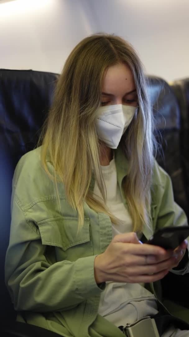 乘坐白色呼吸机的女性游客在飞机上使用手机 — 图库视频影像