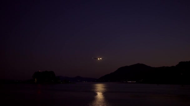 Avionul de pasageri aterizează deasupra mării de noapte, luminii și întunericului — Videoclip de stoc