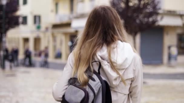 Kobieta idzie ulicą miasta z plecakiem, turysta rozgląda się po zabytkach — Wideo stockowe