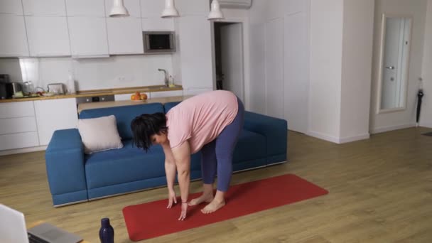 Sovrappeso donna che esegue yoga asana guerriero a casa — Video Stock