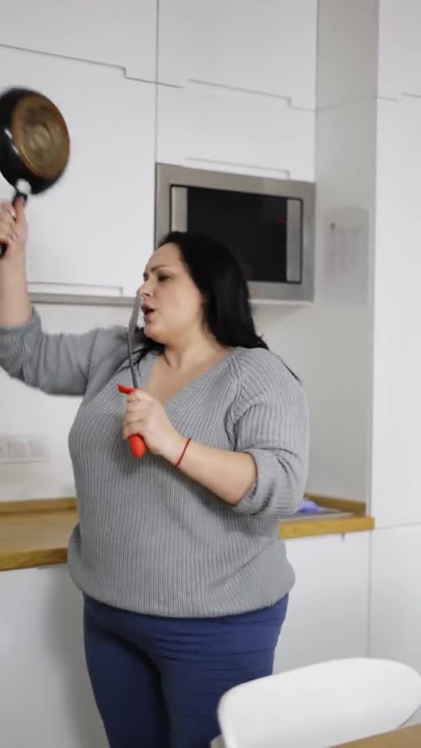 Attractive plus size young woman dancing energetic with pan and ladle in hands — Stock Video