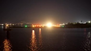 Yolcu uçağı gece denizi, ışıklar ve karanlık üzerinden kalkıyor.