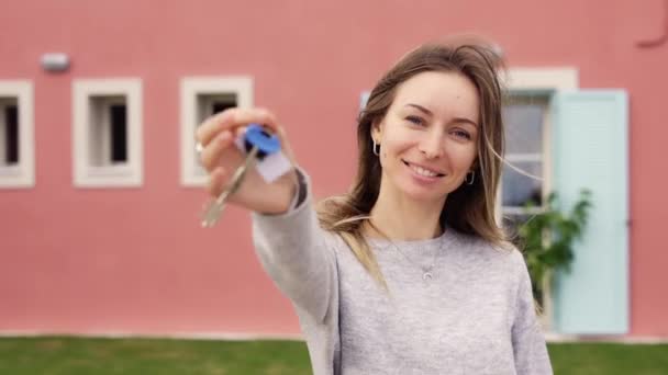 Gelukkig vrouw tonen sleutels van nieuw appartement buiten nieuw huis — Stockvideo
