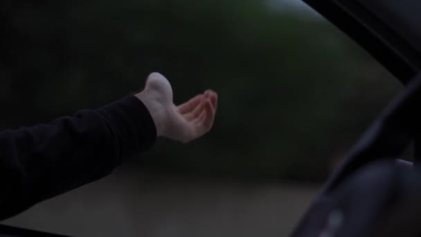 Uma mão de homem está pegando o vento enquanto dirige um carro em um dia chuvoso — Vídeo de Stock