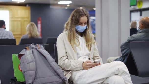 Kobieta turysta noszenie maski ochrony medycznej przy użyciu telefonu komórkowego na lotnisku — Wideo stockowe