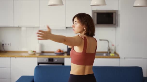 Женщина поворачивает руки, практикует йогу дома, вид сзади — стоковое видео