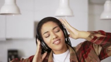 Genç Afro-Amerikan kadın portresi kulaklık takıyor evde müzik dinliyor, ağır çekimde.