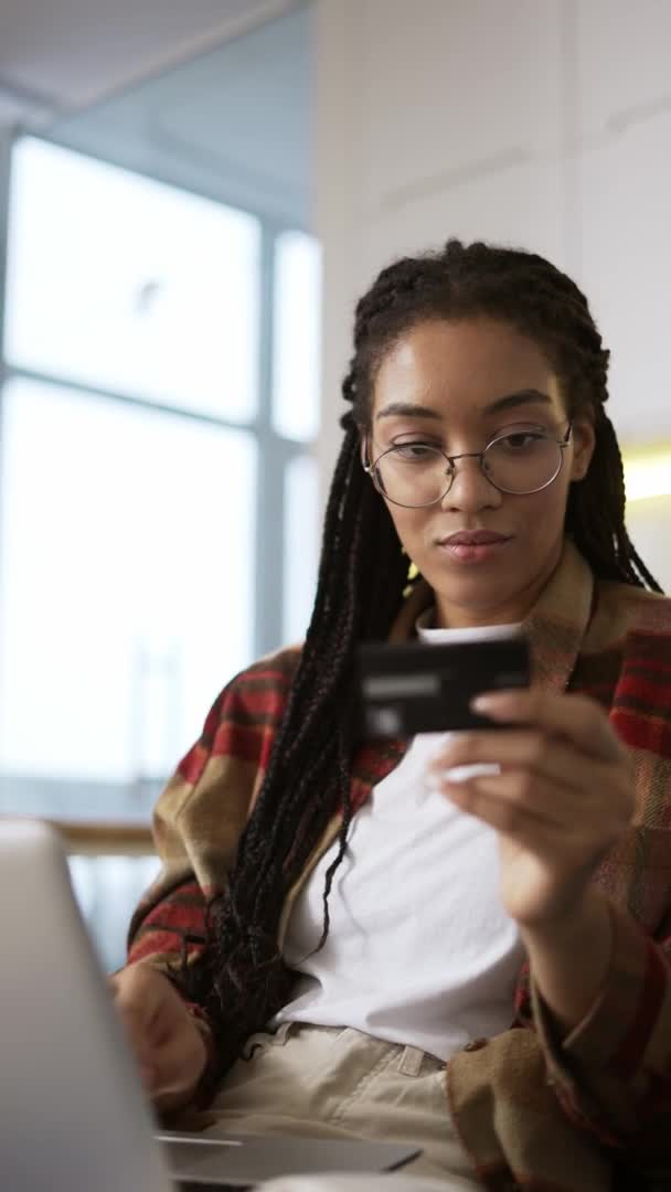 Joven afroamericano celebración de la tarjeta de crédito con el ordenador portátil y la compra en línea, de cerca — Vídeos de Stock