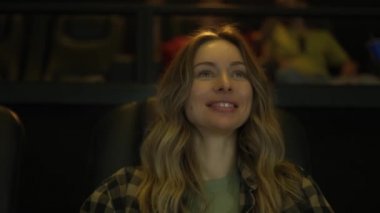 Neşeli kadın sinemada komedi filmi izliyor, patlamış mısır yiyor.