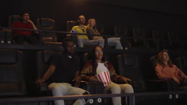 Mixta corrió joven pareja sentada en el cine y viendo el cine — Vídeo de stock