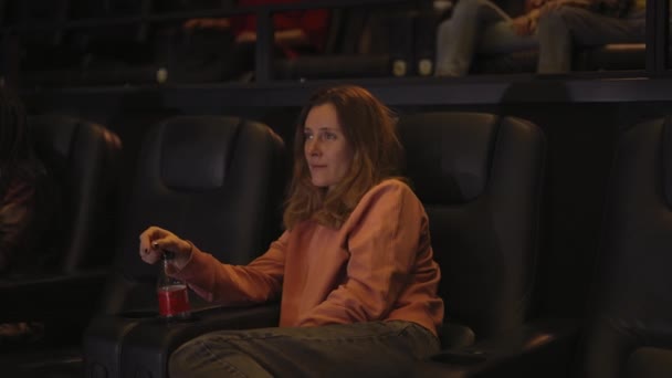 Γυναίκα κάθεται στην πολυθρόνα βλέποντας μια ταινία στο σινεμά μόνη της, πλαϊνή άποψη — Αρχείο Βίντεο
