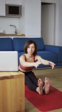 Forward Bend pozisyonunda genç esmer kadın video turtorial ile mat üzerinde