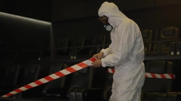 Cuarentena por pandemia de coronavirus: dos hombres disfrazados de protección estiran las cintas de advertencia sobre los asientos — Vídeo de stock