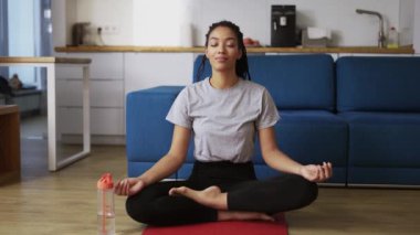 Afrika kökenli Amerikalı kadın yoga minderinde poz veriyor. Kapalı gözler.