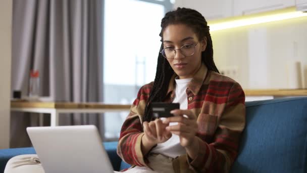Ung afrikansk amerikan håller kreditkort med hjälp av laptop och köpa online — Stockvideo