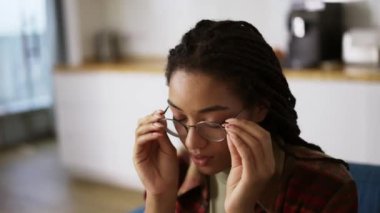 Yorgun Afrikalı Amerikalı kadın gözlüğünü çıkarıp kanepeye uzandı.