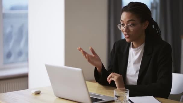 Afro amerykanka dziewczyna biznes kobieta siedzi przy stole w biurze za pomocą laptopa biorąc wideo rozmowy — Wideo stockowe