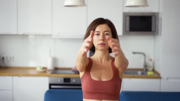 Женщина, выкручивающая руки, практикующая йогу дома, вид спереди — стоковое видео