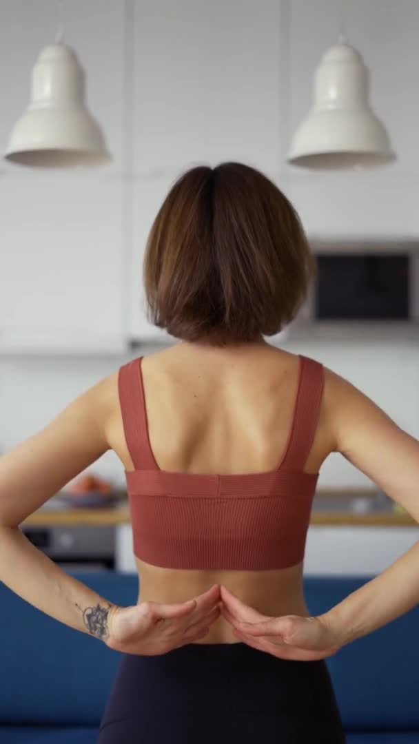En smal kvinna som knyter händerna bakom ryggen, yogakoncept — Stockvideo