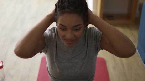 Młoda Afroamerykanka ćwiczy w salonie, pada zmęczona na macie — Wideo stockowe