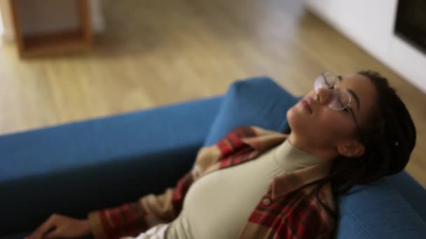 Εξαντλημένη Αφροαμερικανή με γυαλιά ξαπλωμένη στον καναπέ. — Αρχείο Βίντεο