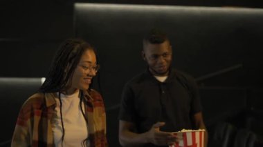 Afrikalı Amerikalı genç bir çift sinema salonuna film izlemeye geldi, kovadan patlamış mısır yiyorlardı.