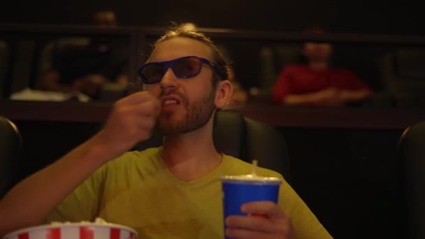 En man i 3D-glasögon tittar på komedi film på bio och äter popcorn — Stockvideo