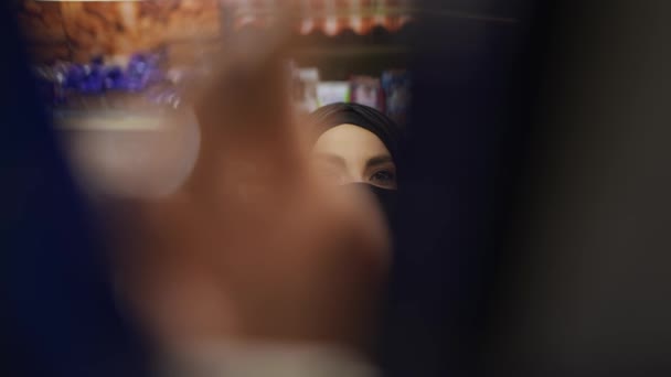 Kvinna i hijab och mask tar produkten från hyllan, bilder inifrån — Stockvideo