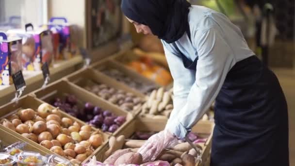 Perempuan berhijab mengisi kembali sayuran di atas stok di supermarket — Stok Video