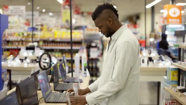 L'acquirente sceglie un computer portatile in un moderno negozio di tecnologia — Video Stock