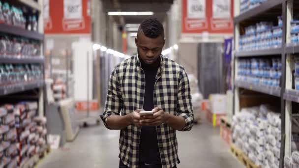 Un uomo con un telefono che fa shopping in un magazzino. — Video Stock