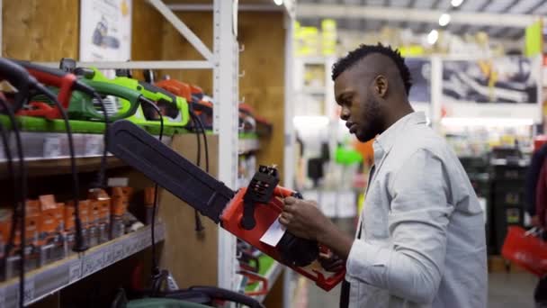 Uomo concentrato esaminando motosega in un negozio di ferramenta — Video Stock